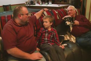 Brad Harbert sitting on sofa with his son, father, and their dog