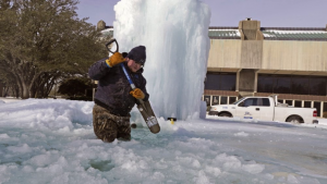 A municipal worker breaking ice on a frozen fountain in Richardson, Texas, on Tuesday, Feb. 16, 2021