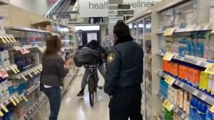 Shoplifting suspect Jean Lugo-Romero filmed last week riding past a Walgreens security guard with a black garbage bag full of stolen goods