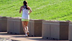 woman jogging near grass bank
